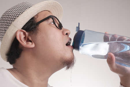 Portrait of healthy good looking Asian male drink and showing mineral water in bottle