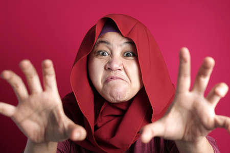Portrait of Asian muslim lady wearing hijab shows angry screaming gestureの写真素材