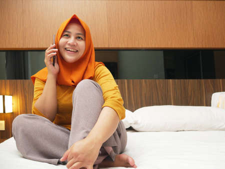 Portrait of muslim lady wearing hijab talking on phone, happy smiling expression having good newsの写真素材