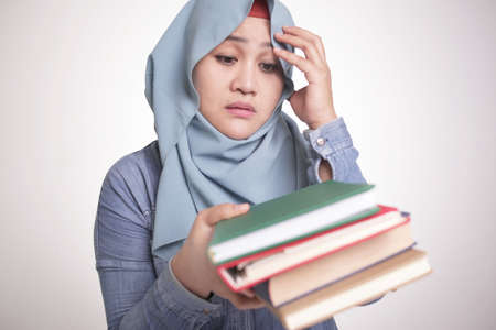 Portrait of cute Asian muslim woman sick and tired reading too much books
