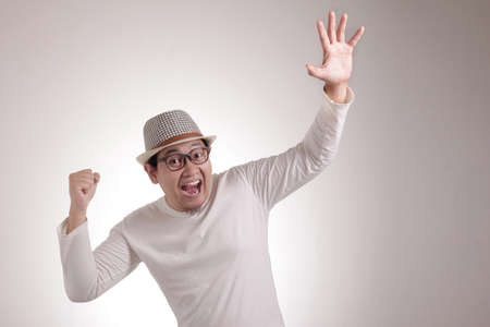 Portrait of successful young Asian businessman shows winning gesture, celebrating victory. Hands...
