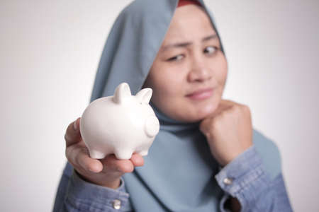 Young happy successful Asian businesswoman holding piggy bank in hand, future saving investment...