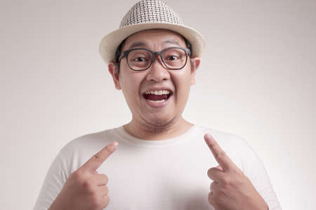 Portrait of happy Asianman smiling and pointing himself, confidence concept, close up portrtait against white backgroundの写真素材