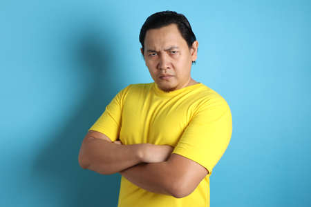 Portrait of funny Asian man showing cynical unhappy angry facial expressionの写真素材