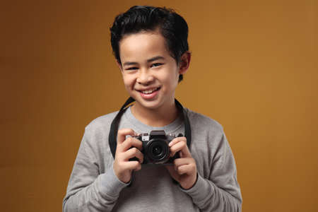 Happy Asian boy doing photography leisure activity, kid as photographer taking picture with his...