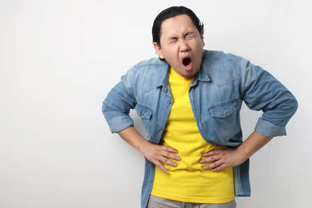 Portrait of young Asian man squezze his stomach for having stomachache painの写真素材
