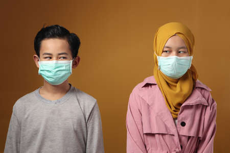 Boy and girl, muslim brother and sister wearing medical mask to prevent covid coronavirus infection, social distancingの写真素材