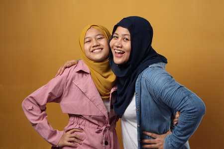 People and family, happy smiling Asian muslim mother hugging daughter against yellow background, motherhood conceptの写真素材