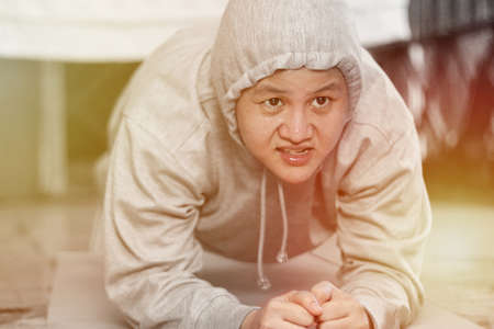 Close up portrait of Asian woman doing hard plank, exercising her abs at home, trying to lose body...