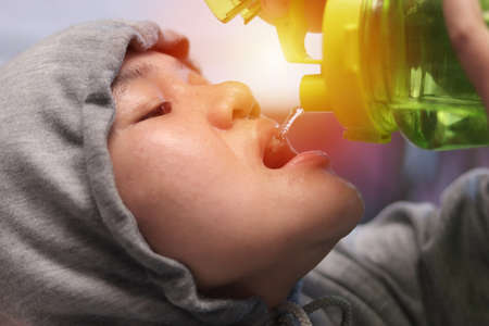 Close up portrait of Asian woman looks tired after intense training or hard workout and drink water to keep hydratedの写真素材