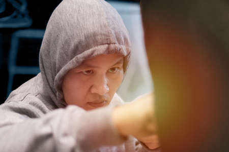 Asian woman boxer hitting punching bag, workout at home gym, female practice martial arts...