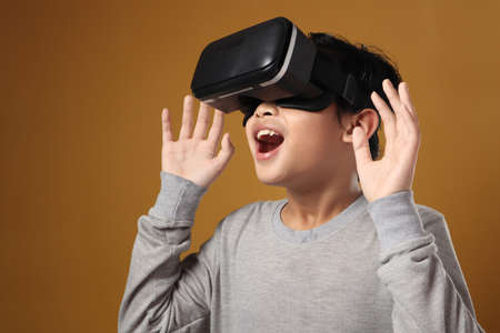 Happy young boy wearing virtual reality VR goggles watching movies or playing video games.  Funny...