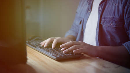 Male anonymous businessman entrepreneur working overtime alone in a dark office at the evening, work hard for his ambition of successの写真素材