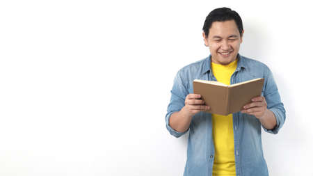Portrait of Asian man wearing casual white shirt looked happy and smiling while reading a book