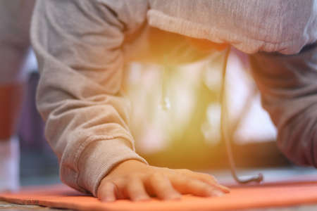 Close up portrait of Asian woman doing hard plank, exercising her abs at home, trying to lose body fat and be slimの写真素材