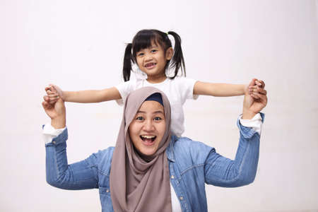 Muslim mother wearing hijab smiling while playing with her baby girl, mom and daughter love each other, happy single parentの写真素材