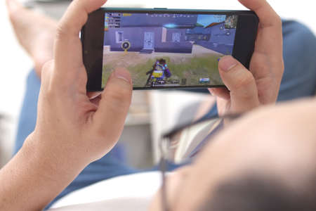Tenggarong, Indonesia. June 20th 2020. Male man gamer relaxing and playing video game on the smartphone. Gaming, technology, lifestyle, e-sport and internet of thingのeditorial素材