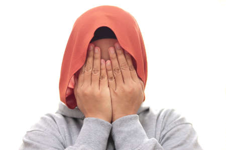Muslim woman wearing hijab covering hiding face with her hands, shy afraid worried guilty gesture, isolated on whiteの写真素材