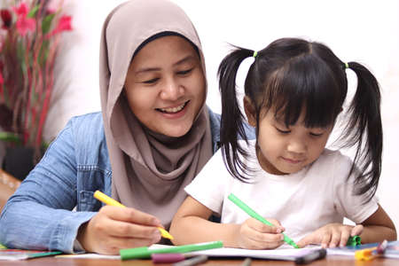 Asian muslim mother drawing with her daughter, single mom teaching baby girl, happy family concept  の写真素材