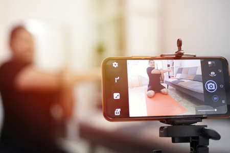 Male fitness instructor stream broadcast or record a video lesson on training sport at home for the...