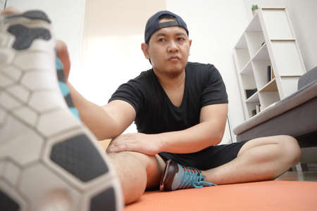 Asian male doing exercise at home to stay healthy on new normal lifestyle, indoor home workout...