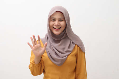 Happy cheerful beautiful Asian muslim lady wearing hijab waving to camera, doing selfie or video...