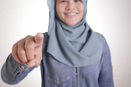 Portrait of Asian muslim lady wearing hijab pointing forward to camera as if choosing you gesture, business recruitment hiring conceptの写真素材