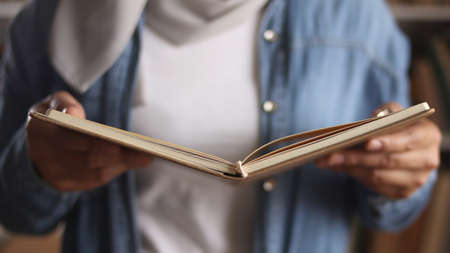 Anonymous woman reading book in library, eduational concept. Happy smiling expression when doing leisure activityの写真素材