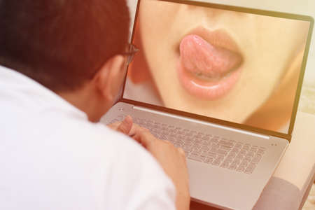 Anonymous man lying on sofa watching erotic porn movie on his laptop