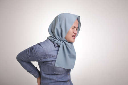 Portrait of muslim woman suffers from lower back pain, health and medical concept