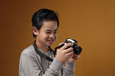 Happy Asian boy doing photography leisure activity, kid as photographer taking picture with his...