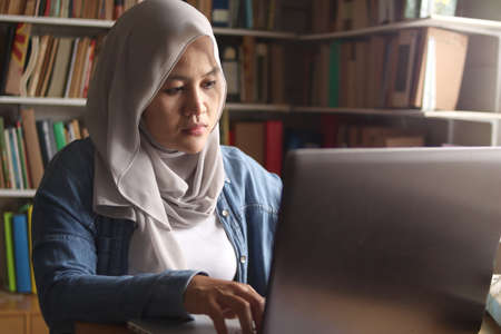 Asian muslim woman studying in library, exam preparation concept. Female college student doing...