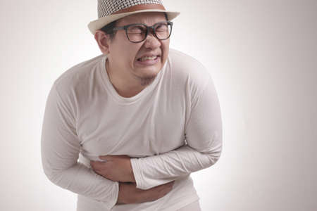 Portrait of young Asian man squezze his stomach for having stomachache pain