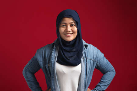 Asian muslim woman wearing hijab smiling friendly with hands on hip, confident successful woman...