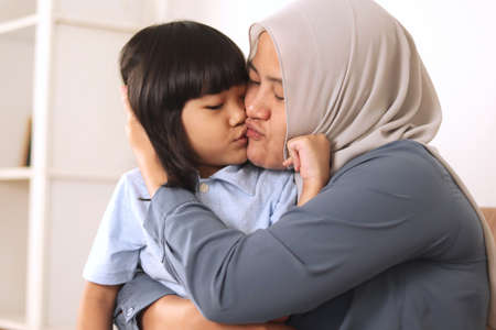 Muslim mother wearing hijab smiling while playing with her baby girl, mom and daughter love each other, happy single parentの写真素材