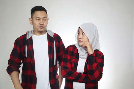 Asian muslim couple looking each other with suspicious looking, over grey backgroundの写真素材