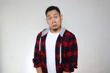 Portrait of young funny Asian man shocked to see something bad, gasp stunned expression over greyの写真素材