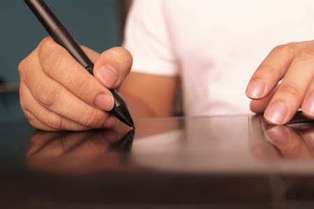 Close up of graphic designer working with pen tablet, using digital pen tablet for photo editing
