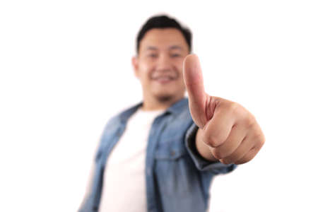 Portrait of young Asian man shows thumbs up sign, happy smiling person, OK deal conceptの写真素材