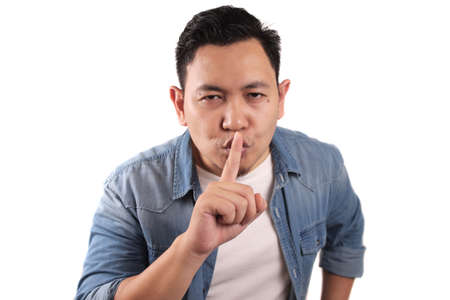 Portrait of young Asian man asking to be quiet, shushing gesture, silence conceptの写真素材