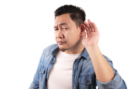 Young asian man listen whispers with funny face. Curious. Intently listen in on juicy gossip. Conversation news, privacy violation conceptの写真素材