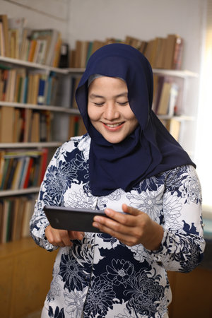 Asian muslim woman using phone and smiling. Feeling happy. Female doing communication on her smart phone, sending message or browsing onlineの写真素材