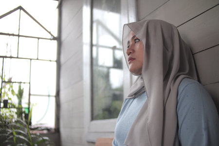 Sad muslim woman contemplating something while sitting on the outside of her home