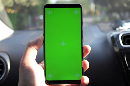 Close up image of smart phone on car mock up, riding a car with smartphone map navigation concept, blank phone green screen templateの写真素材