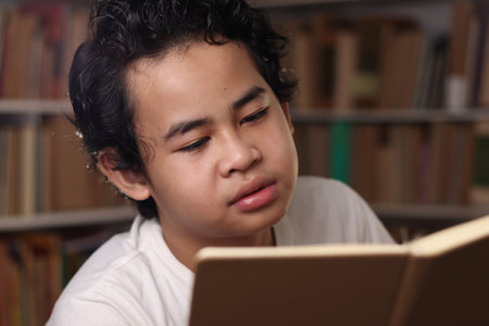 Smart Asian student boy reading a book in library, educational concept, kid learning at home