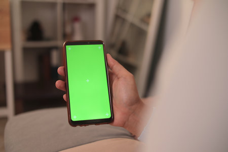 Close up image of smart phone mockup, woman holding phone with green screen templateの写真素材