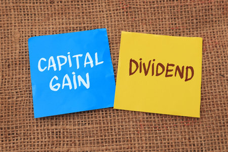 Capital gain and dividend, text words typography written on paper against wooden background, life and business motivational inspirational conceptの写真素材