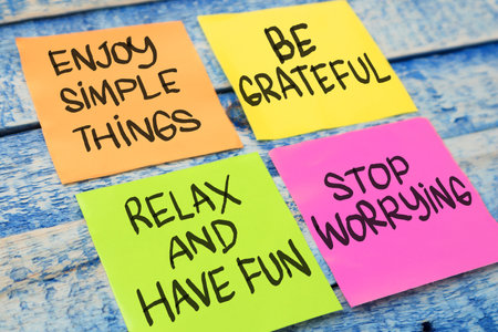 Enjoy simple things be grateful relax have fun stop worrying, text words typography written on paper against wooden background, life and business motivational inspirational conceptの写真素材