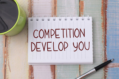 Competition develop you, text words typography written on book against wooden background, life and business motivational inspirational conceptの写真素材