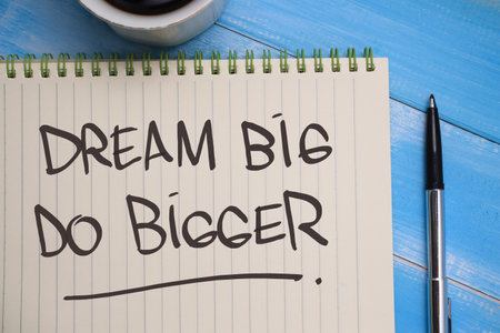 Dream big do bigger, text words typography written on book against wooden background, life and business motivational inspirational concept